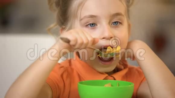 可爱的女孩吃谷类食品特写开胃早餐早上玉米片餐视频的预览图