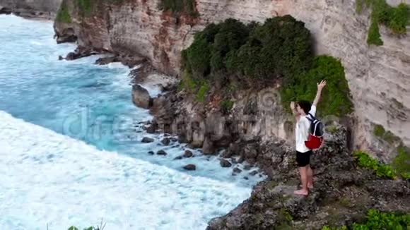 成功的年轻人剪影站在海洋悬崖空中举起武器快乐自由的概念视频的预览图