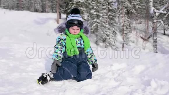 冬天公园里坐在雪地上的一个孩子在清新的空气中行走健康生活方式视频的预览图