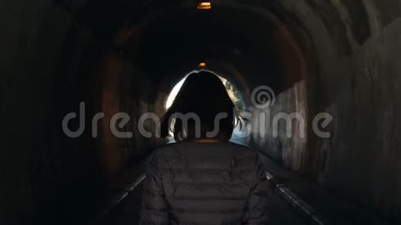 女人在黑暗中独自行走灯光在隧道概念的尽头后景跟随拍摄旅游度假视频的预览图