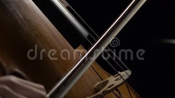 大提琴在黑暗的房间里演奏弦乐侧视慢动作视频的预览图