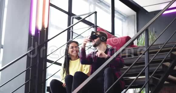 微笑的非洲大小姐与一个男子探索虚拟现实眼镜在现代建筑坐在视频的预览图