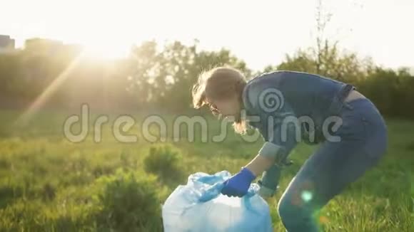 日落时美丽的女孩在一个大塑料袋里收集垃圾生态概念视频的预览图