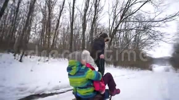 冬天快乐的童年父亲和孩子们在雪林里的雪橇上散步视频的预览图