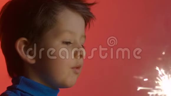 五岁的男孩看烟花红色背景下的火花视频的预览图