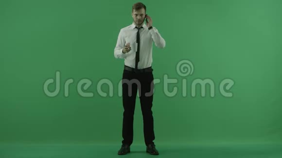 一个男人在打电话喝着绿色背景的杯子视频的预览图
