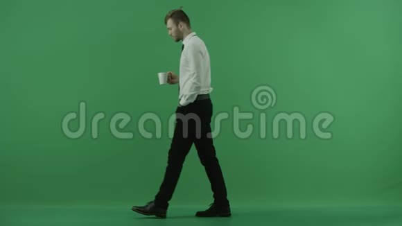 一个男人从一边走到另一边然后从绿色屏幕上的杯子里喝水视频的预览图