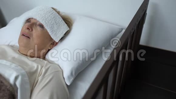 患病的成熟妇女躺在病床上前额受压迫发烧或流感视频的预览图