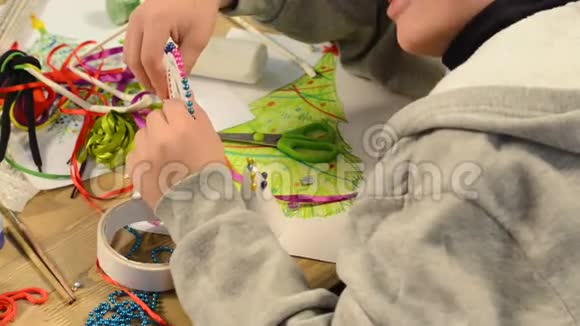 男孩正在为假期做装饰工艺品及玩具圣诞树等画水彩上景艺术作品视频的预览图