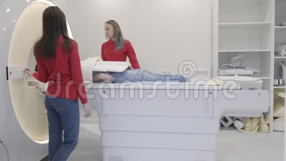 女性与躺着的男性病人开启核磁共振扫描仪视频的预览图