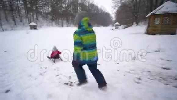活跃的寒假精力充沛的孩子们在雪林里和雪橇一起玩耍和跑步视频的预览图