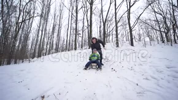 活跃的孩子骑在雪橇上从雪山森林家庭假日视频的预览图
