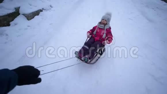 活跃的寒假手快带着快乐的小女孩在雪道上雪橇视频的预览图
