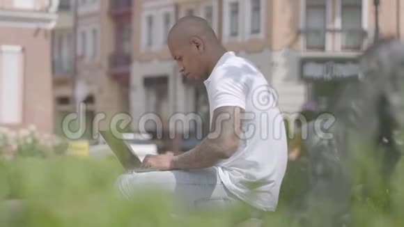 英俊的中东秃顶男子在街上工作笔记本电脑坐在长凳上自由职业概念这就是视频的预览图