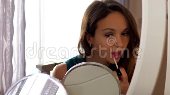慢动作亲密的女人用镜子上的光泽组成嘴唇视频的预览图