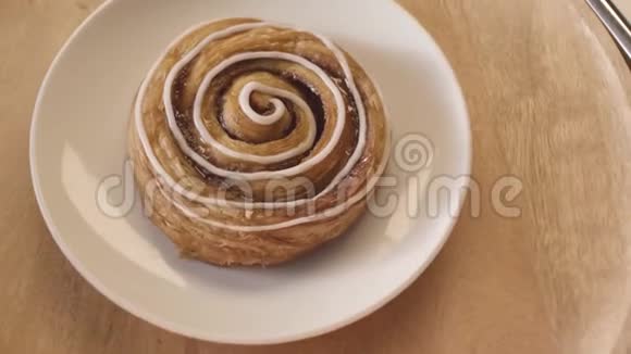 顶部的美味面包蜗牛与白色釉旋转同时躺在玻璃板库存录像把甜蜜的东西收起来视频的预览图