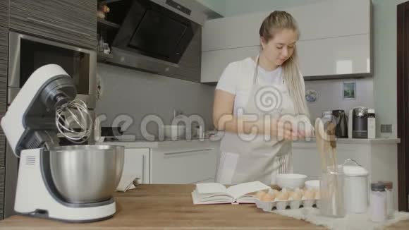 家庭主妇在厨房用智能手机阅读食谱视频的预览图