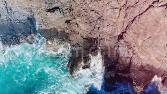 青绿色的海溅到海岸上的岩石上视频的预览图