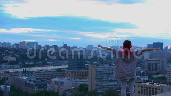 年轻的女性在暮色中看城市的替罪羊屋顶上的粉色头发少年视频的预览图