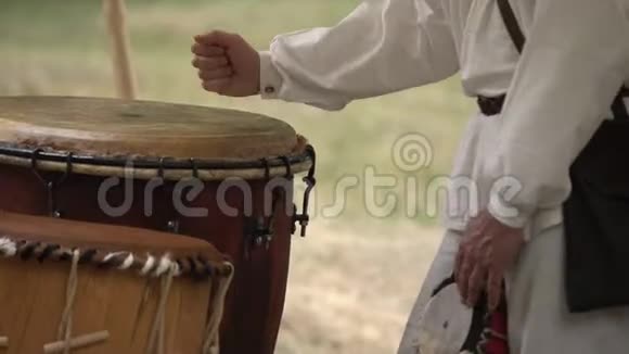 男人在户外玩皮鼓时穿着乡村服装传统部落鼓表演视频的预览图