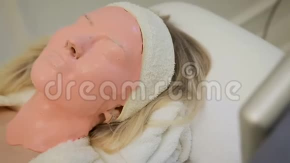 在美容院戴着粉红色面膜的漂亮女人水疗视频的预览图
