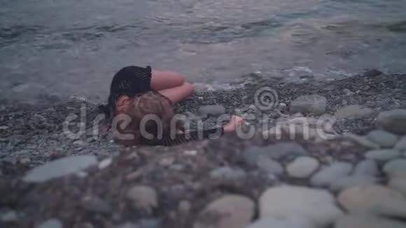 一个年轻的女孩躺在海边没有知觉没有动作面目全非的女人躺在岸上视频的预览图