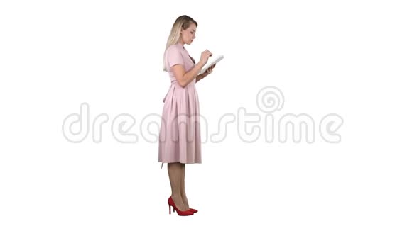年轻女子穿着粉红色连衣裙在白色背景上使用平板电脑视频的预览图