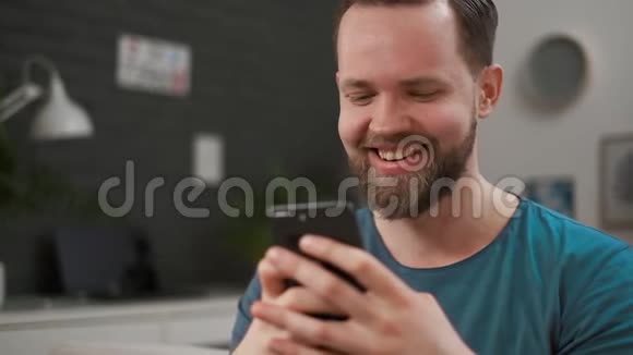 特写一个帅哥在家里在智能手机上打字发短信的肖像男性使用数字移动设备视频的预览图