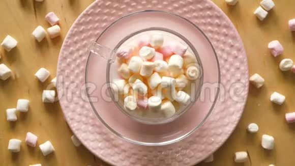 带粉红色盘子和木桌上棉花糖的杯子的俯视图视频的预览图