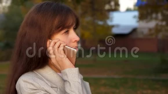 美丽的女人在智能手机上交谈然后去公园快乐的女孩微笑商务女性带着黑色公文包视频的预览图