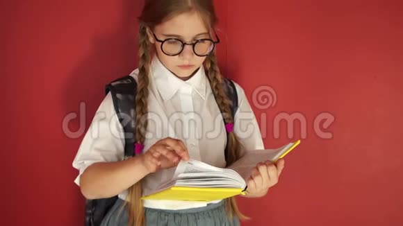 戴着眼镜的女学生仔细地翻阅着这本书红色背景的女学生视频的预览图