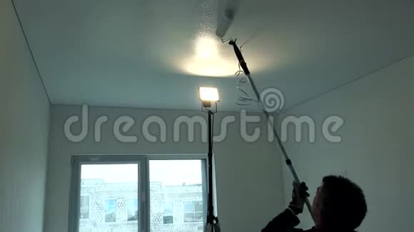 工人用滚筒画天花板男人在房间里画白色的天花板视频的预览图