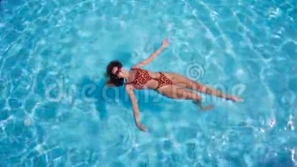从上面看美丽的年轻女子漂浮在清澈的水面上视频的预览图