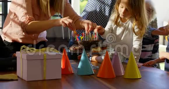 母亲和女儿在客厅4k的生日蛋糕上装饰蜡烛视频的预览图