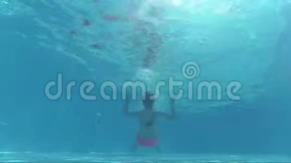 游泳池水下戴面具的快乐女孩躺在背后看着镜头泡泡视频的预览图