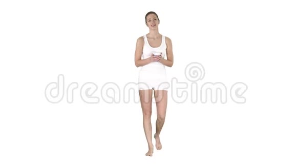 穿着白色运动服的女人拿着一杯咖啡在白色背景上和相机交谈视频的预览图