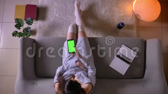 特写镜头年轻迷人的女青少年坐在绿色的彩色屏幕上在电话中聊天视频的预览图