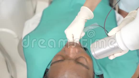 女牙医使用x光机病人躺在牙科椅子上年轻的非洲裔美国男性牙齿不好视频的预览图