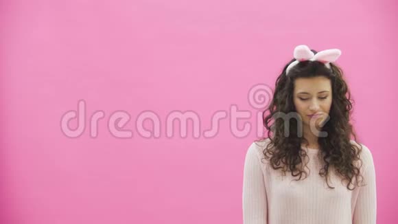 年轻漂亮的夫妇站在粉红色的背景上头上戴着黑黑的耳朵在此期间他给了妻子视频的预览图