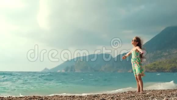 沙滩上张开双臂的小女孩孩子在海边做梦视频的预览图