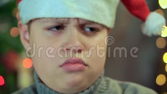 穿着圣诞老人的毛衣和帽子的男孩心烦意乱他没有天赋额外的特写镜头对抗视频的预览图