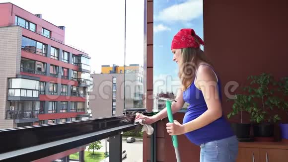 幸福的孕妇在家里用抹布擦玻璃窗户视频的预览图