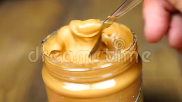 与勺子花生酱混合奶油软面花生酱在罐子背景视频的预览图