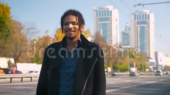 有魅力的非洲裔美国人的肖像带着可怕的表情在道路背景上平静地微笑着进入镜头视频的预览图