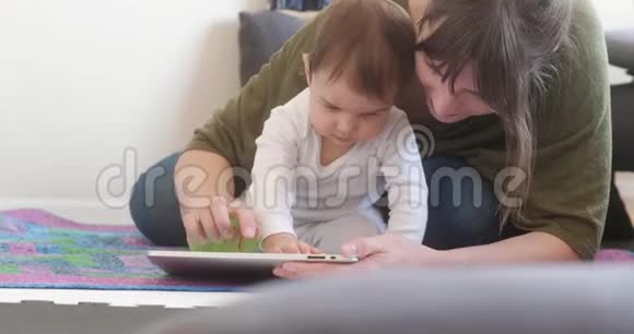 年轻的母亲和她的小女儿用平板电脑视频的预览图