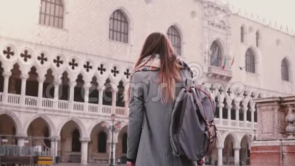 后景女游客带着背包站着兴奋地看着圣马可广场建筑在威尼斯意大利慢动作视频的预览图
