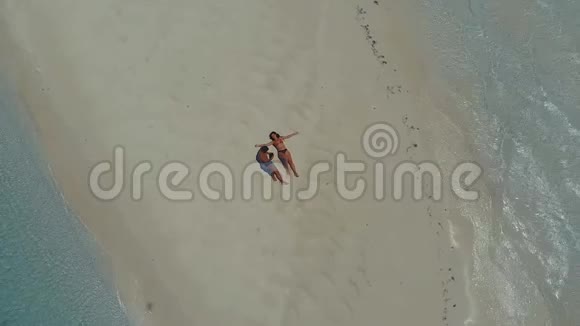 在菲律宾的沙洲上无人机在绿松石水上升起一对旅伴躺在沙滩上视频的预览图