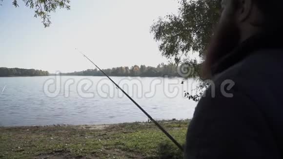 渔夫拿着鱼竿站在河岸上看着水一只鸟飞过水面慢慢视频的预览图
