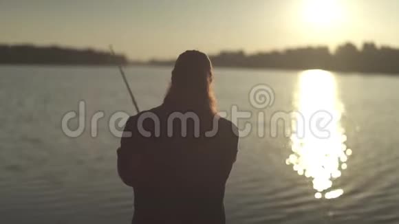 日落时渔民在河的背景上用鱼竿捕鱼费舍尔把线圈旋转起来视频的预览图