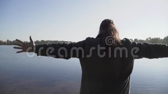 长发男子举起双手朝站在河岸上的天空留着长发扎着辫子的长胡子男人视频的预览图